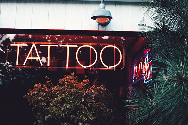 A neon sign that reads TATTOO posted up on a shop