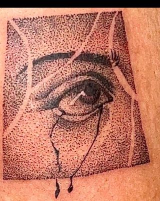 A detailed tattoo of an eye inked on the side of a woman's leg, showcasing intricate designs and shading.