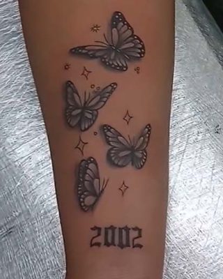 A woman's arm adorned with a delicate tattoo of butterflies