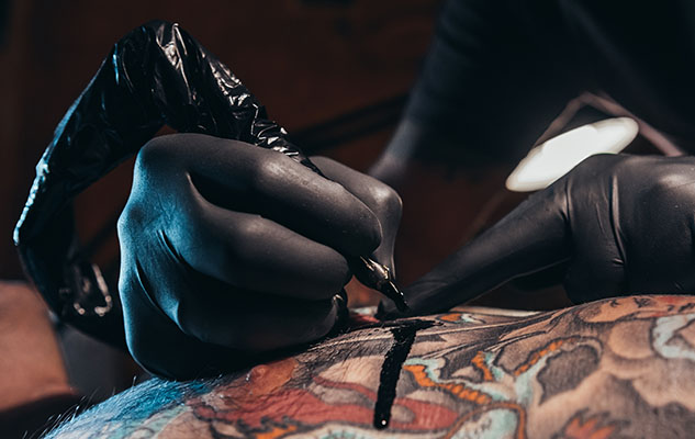 Tattoo artist with gloves and a needle